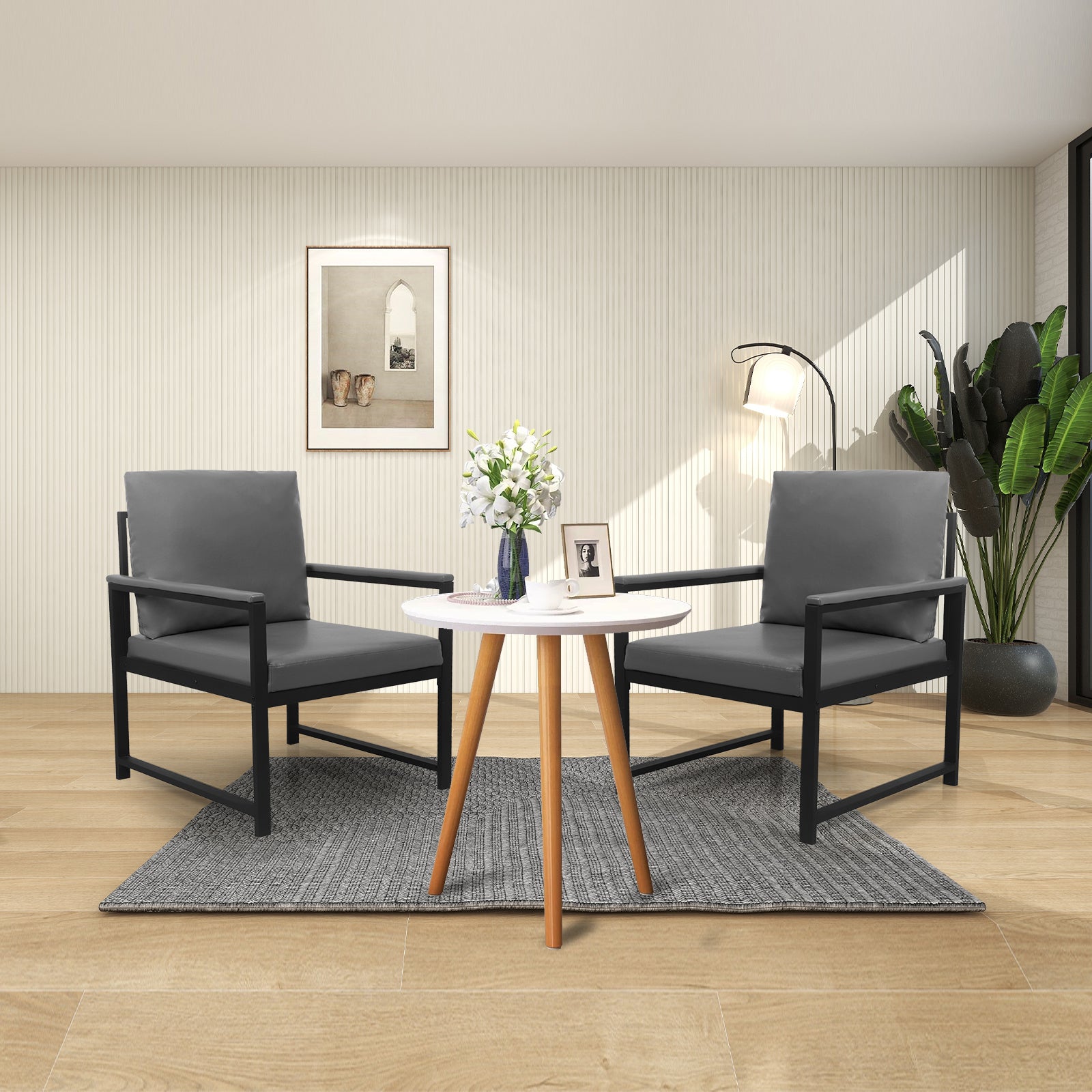 Two modern gray armchairs with black metal frames beside a small round white table