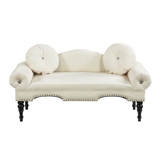 Cream velvet loveseat with ornate details and round throw pillows