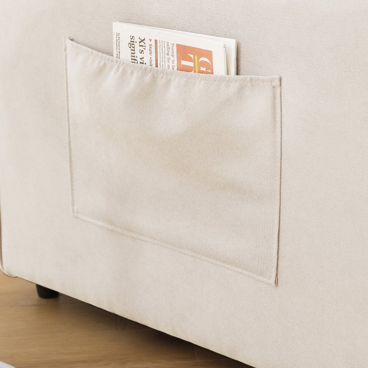 Closeup of a beige linen sofa with a convenient side pocket holding a newspaper