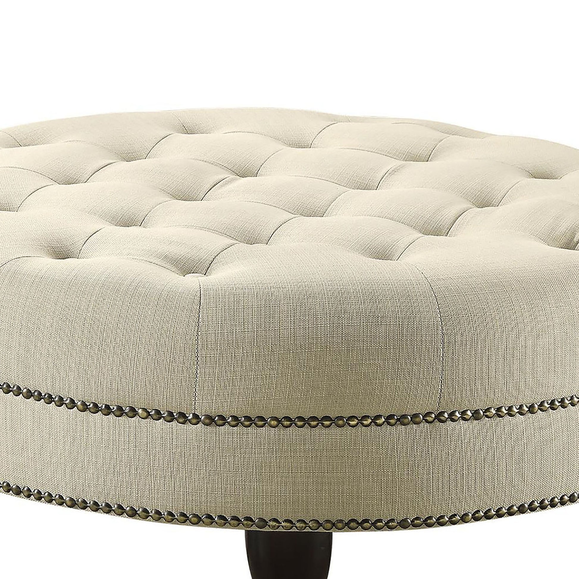 Tufted beige linen ottoman with antique brass nailhead trim detail