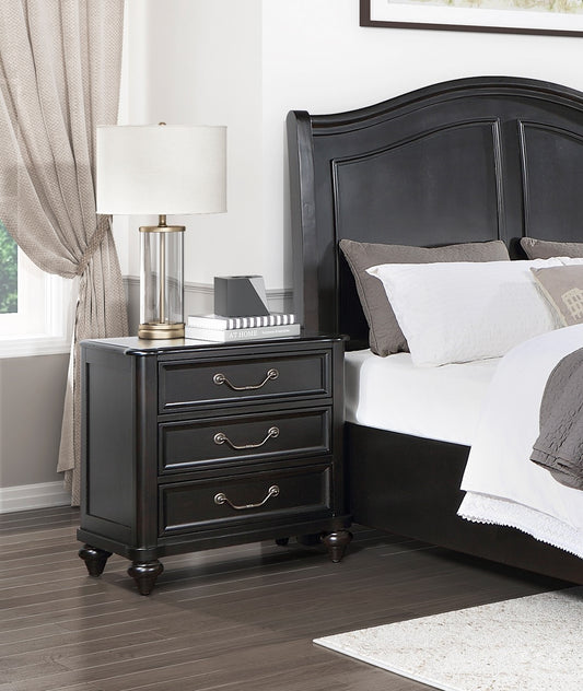 Dark wood nightstand with three drawers and ornate pulls next to a bed