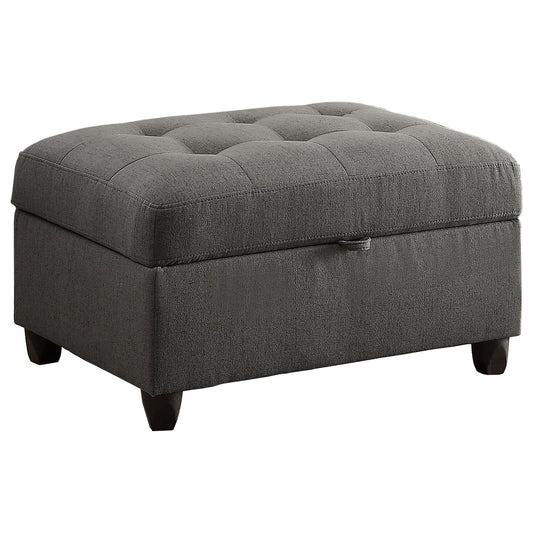 Dark grey tufted storage ottoman with subtle linen texture and dark wood legs
