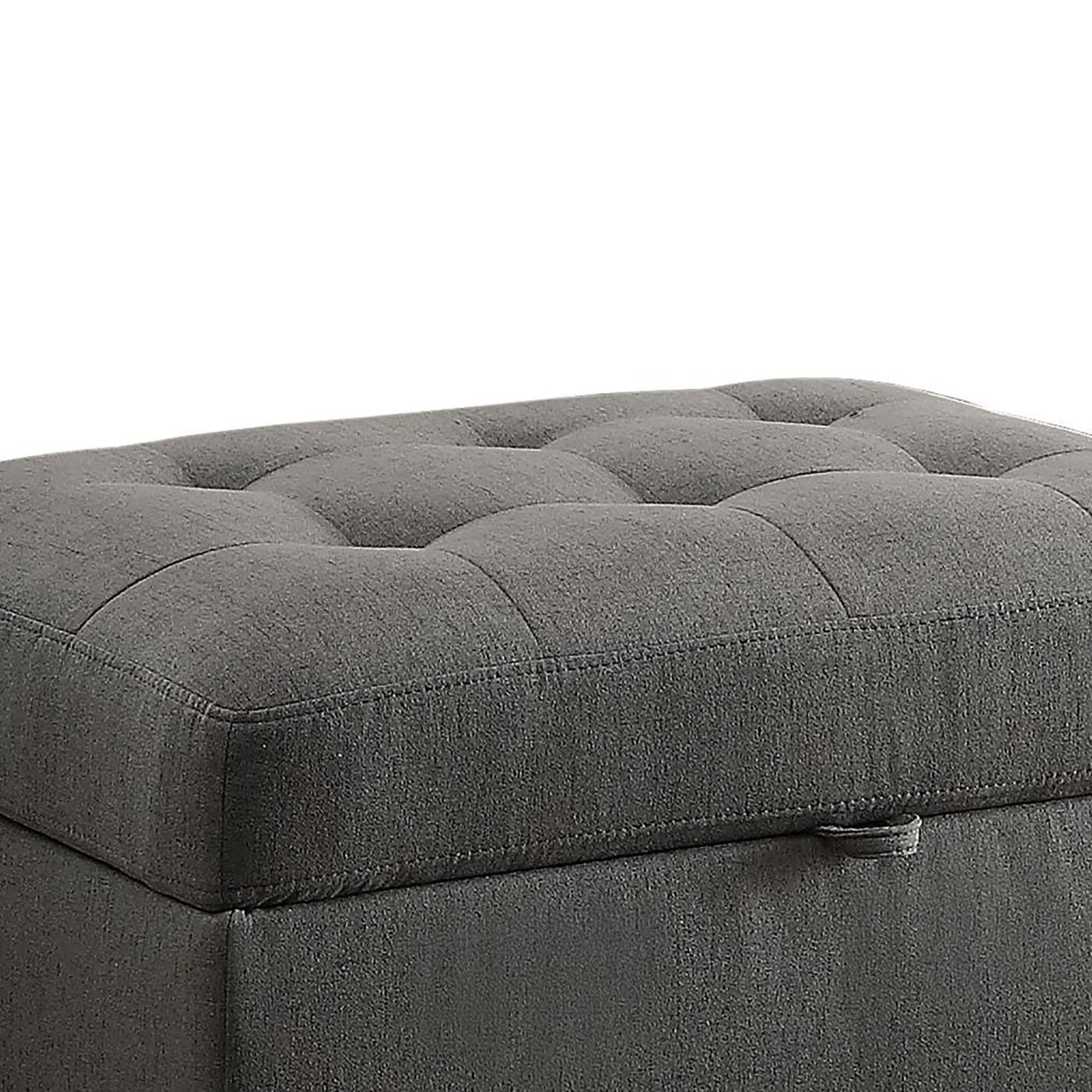 Dark gray fabric storage ottoman with tufted top and side pull tab for easy opening