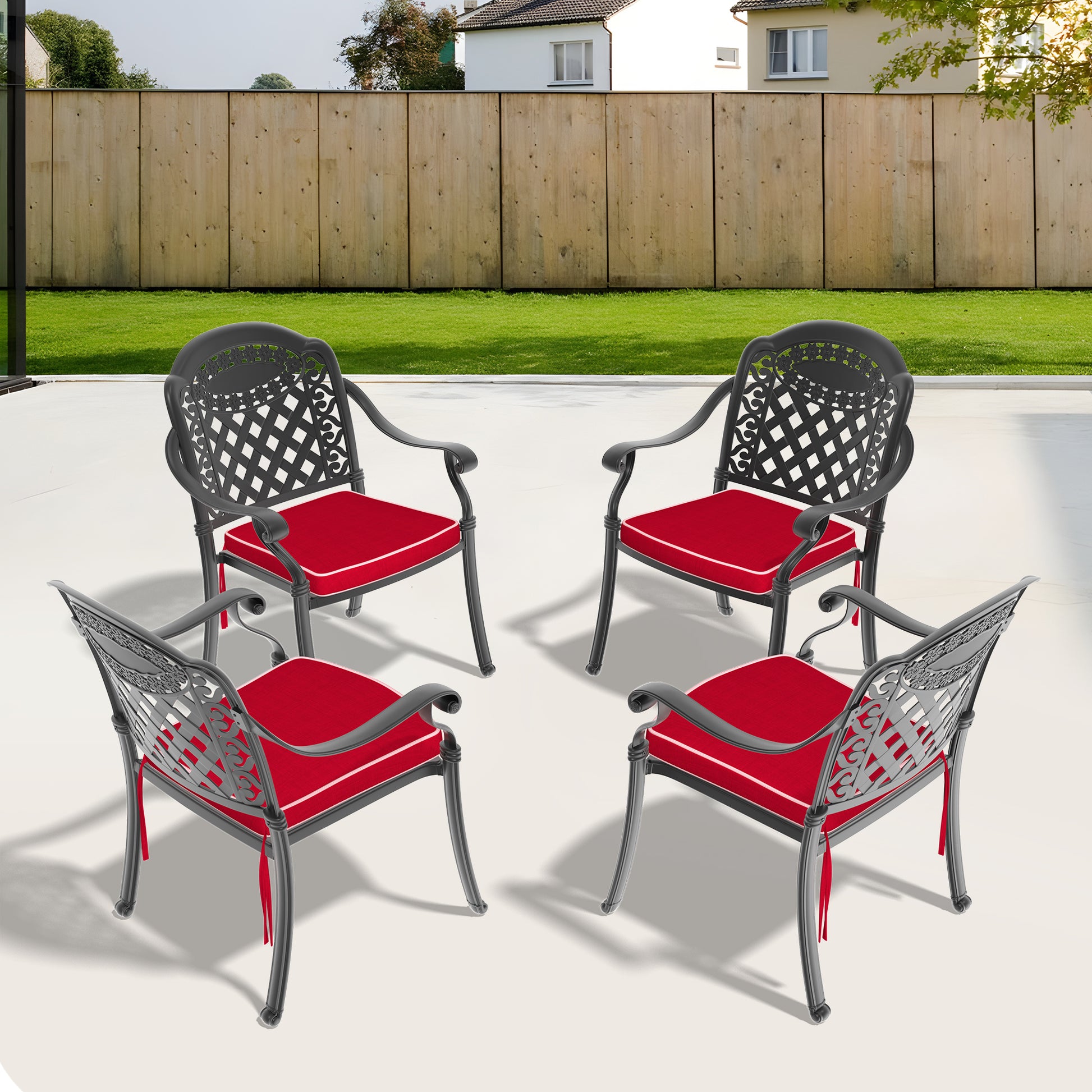 Four dark gray metal patio chairs with ornate backs and red seat cushions arranged on a patio