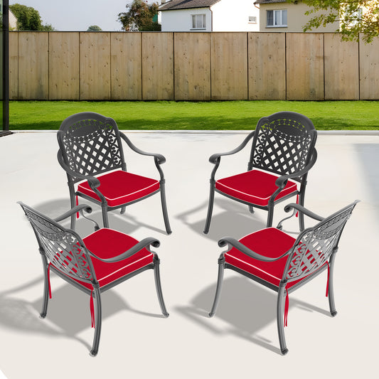 Four dark gray metal patio chairs with ornate backs and red seat cushions arranged on a patio