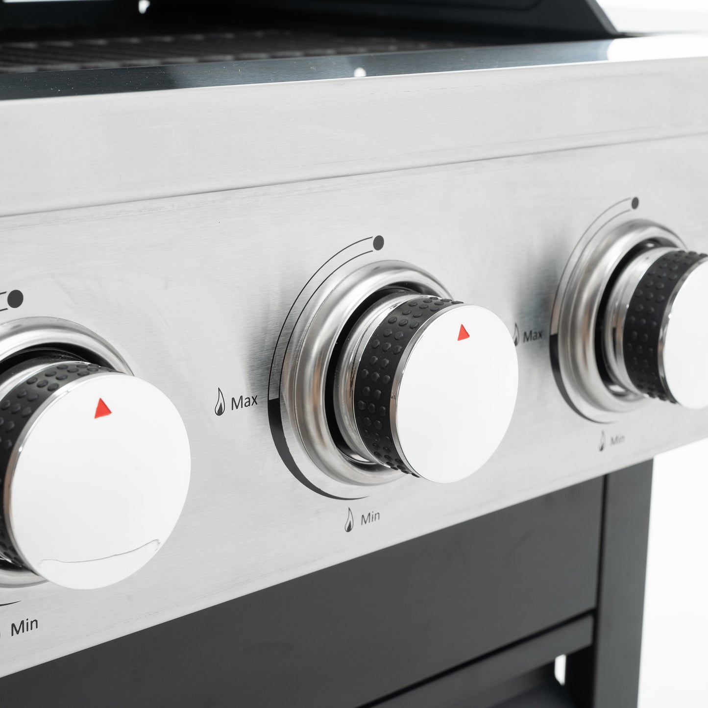 Closeup of a stainless steel gas grill control panel with three silver knobs and flame indicators