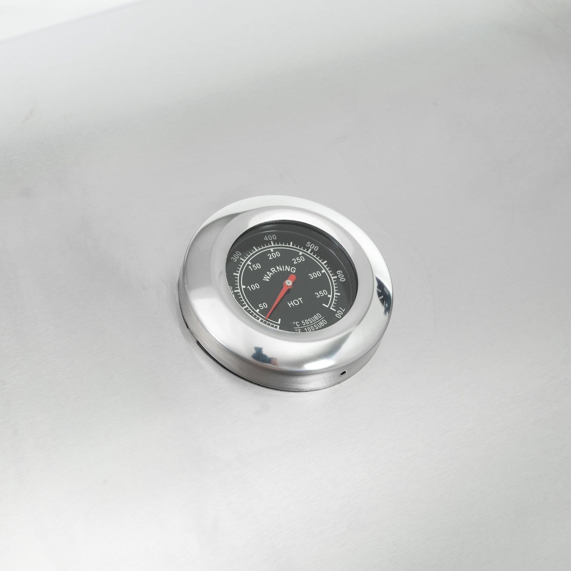 Round stainless steel thermometer dial with red indicator needle showing HOT