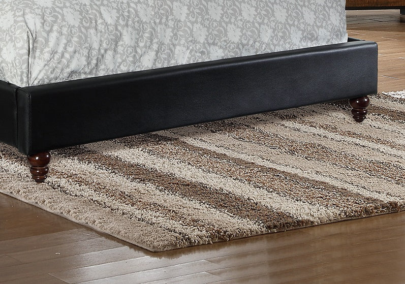 Black faux leather bed frame with a patterned comforter and dark wood legs on a striped rug