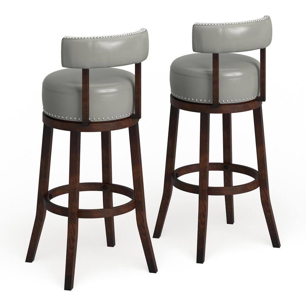 Two grey upholstered swivel bar stools with nailhead trim and dark wood legs