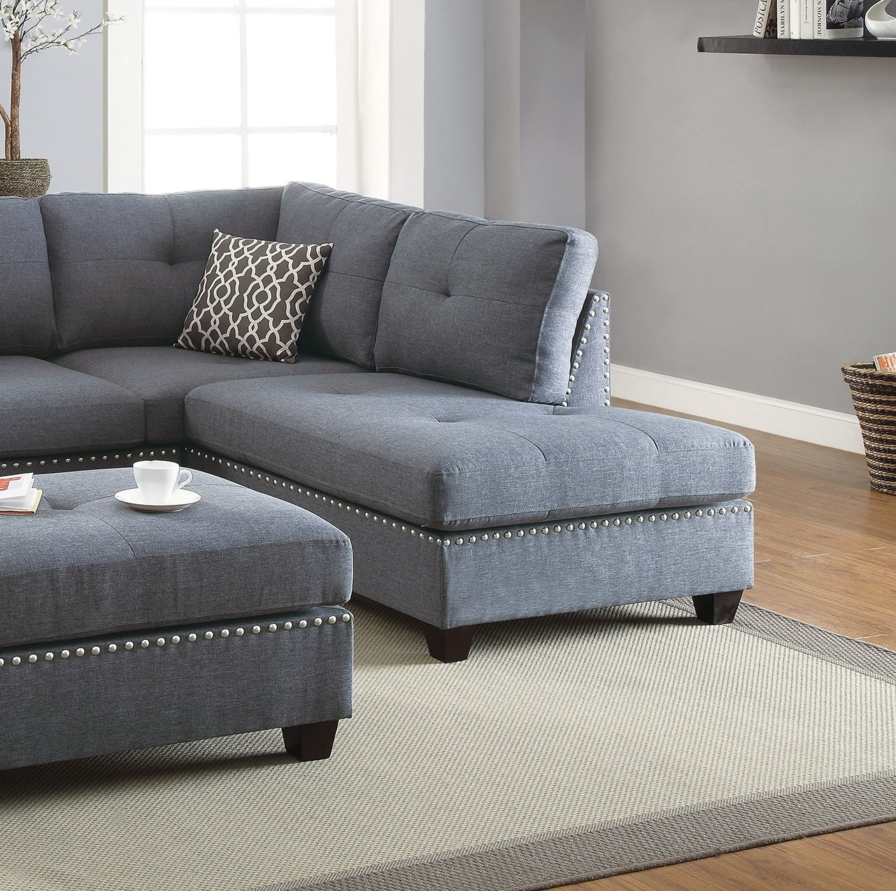 Grey fabric sectional sofa with silver nailhead trim and tufted cushions
