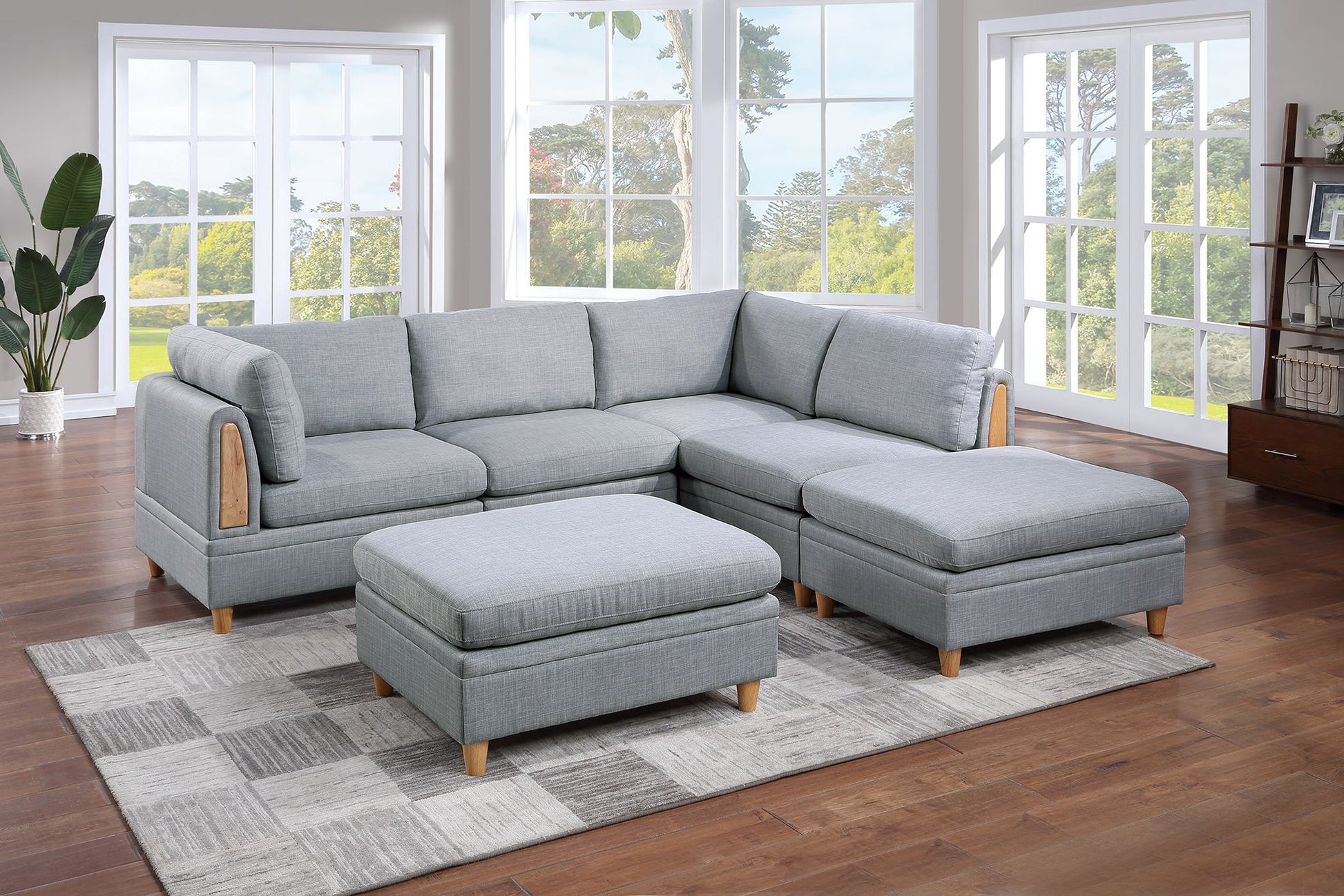 Light gray fabric sectional sofa with wooden accents and matching ottomans on a patterned rug