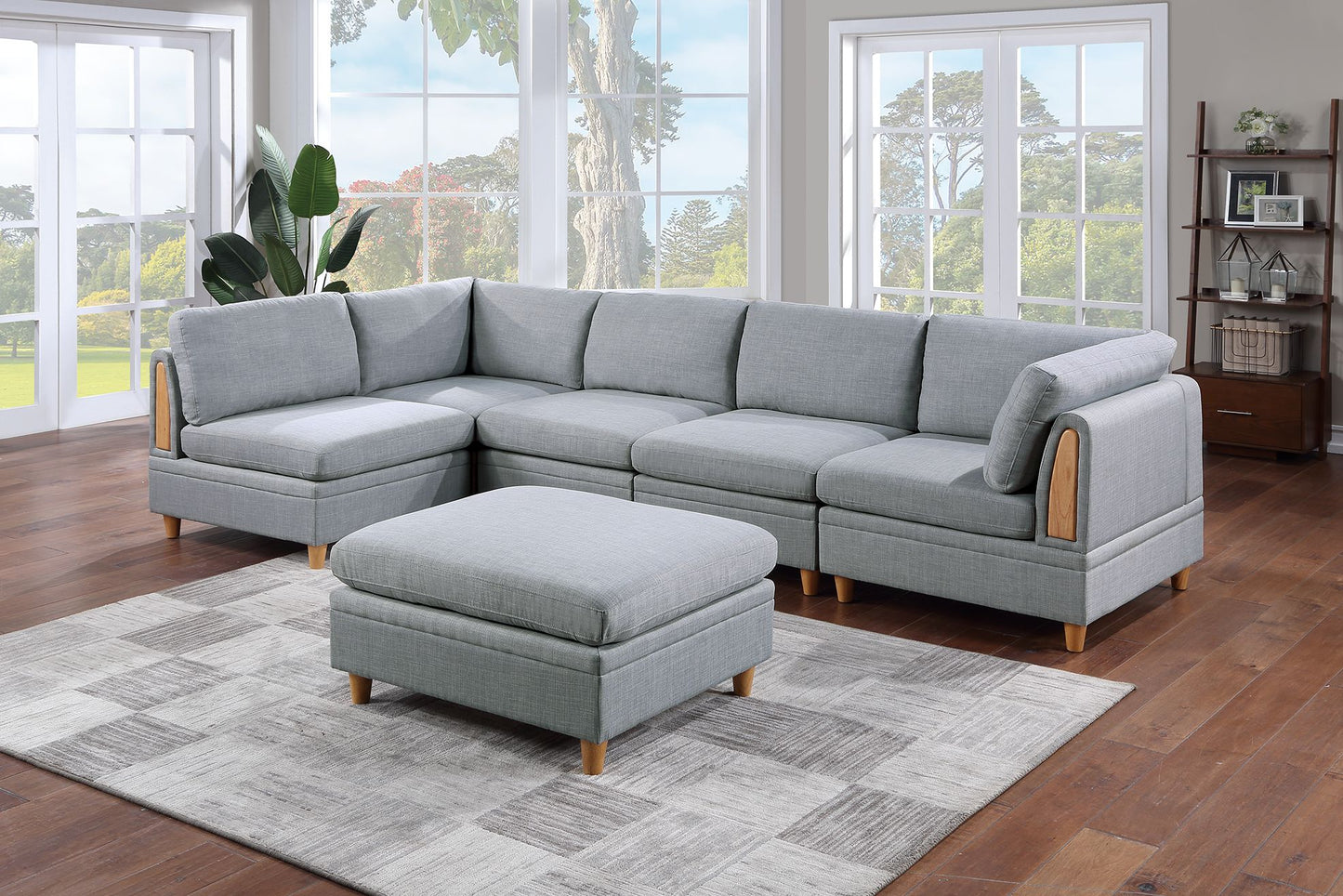 Light gray fabric sectional sofa with wooden accents and matching ottoman on a patterned rug