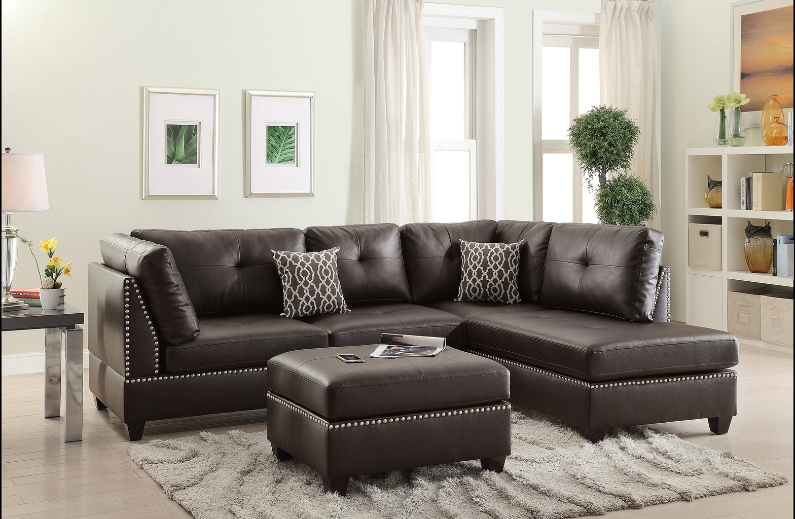 Dark brown tufted leather sectional sofa with silver nailhead trim and patterned throw pillows