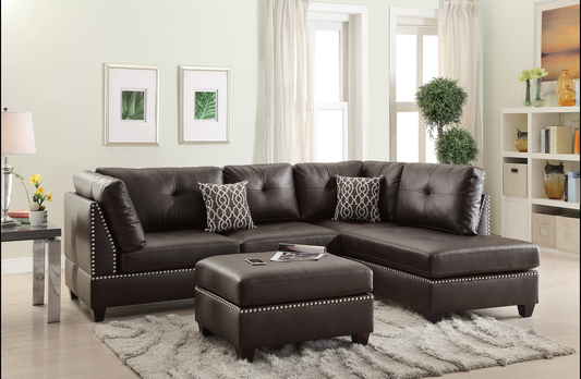 Dark brown tufted leather sectional sofa with silver nailhead trim and patterned throw pillows