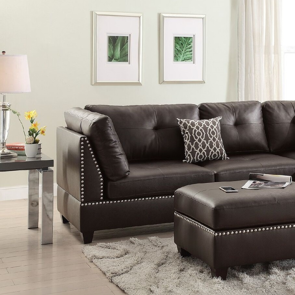 Dark brown tufted leather sectional sofa with silver stud accents and a decorative pillow