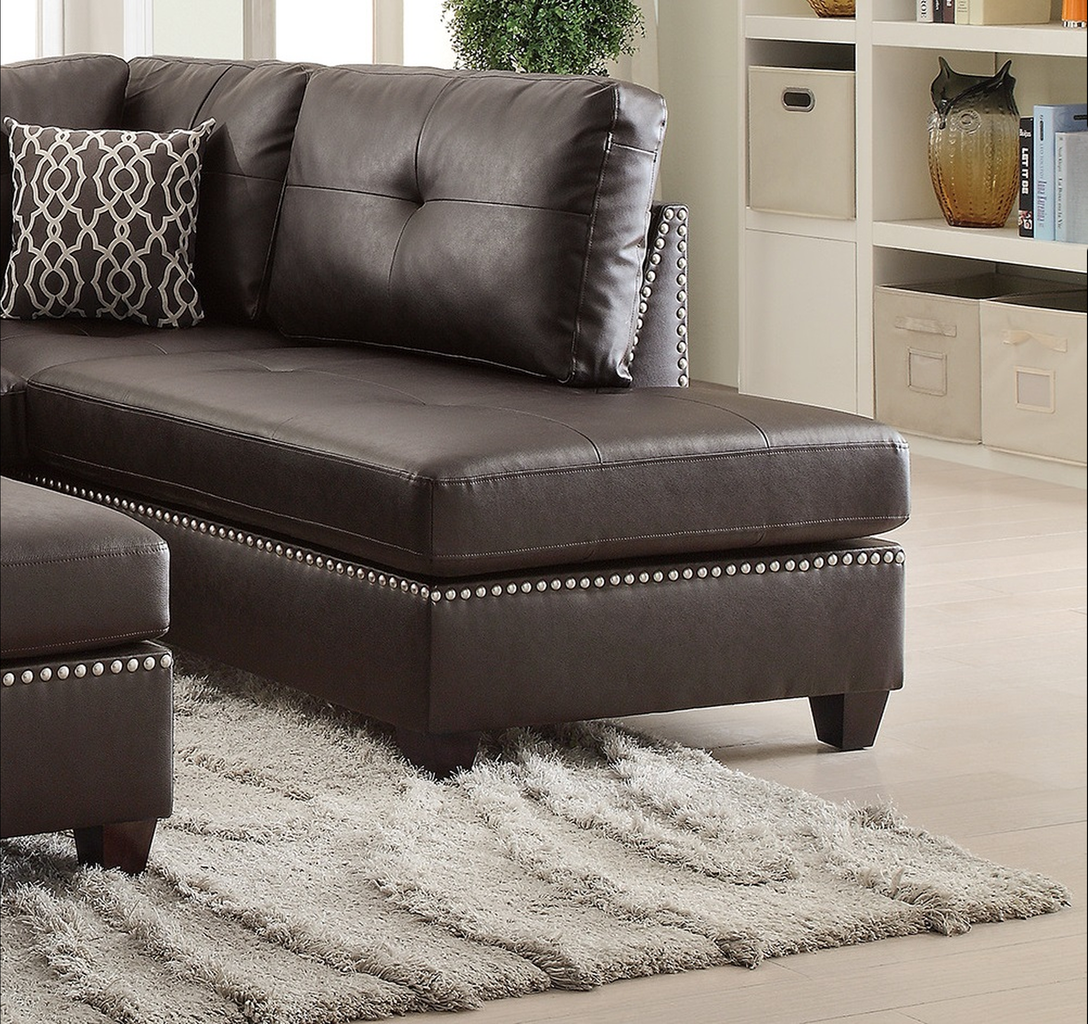 Brown leather sectional sofa with decorative nailhead trim and patterned throw pillow