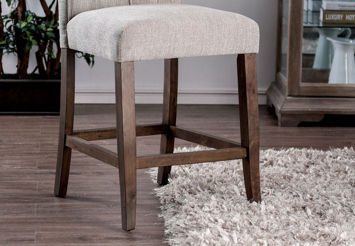 Textured cream fabric counter stool with dark wood legs on a plush rug