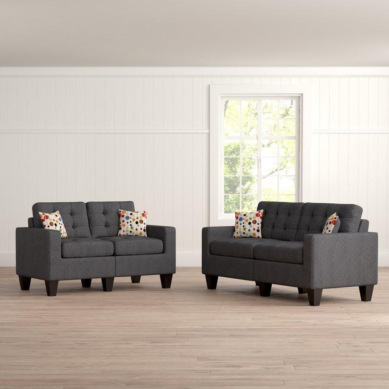 Dark gray loveseat with tufted cushions and decorative pillows ideal for compact living spaces