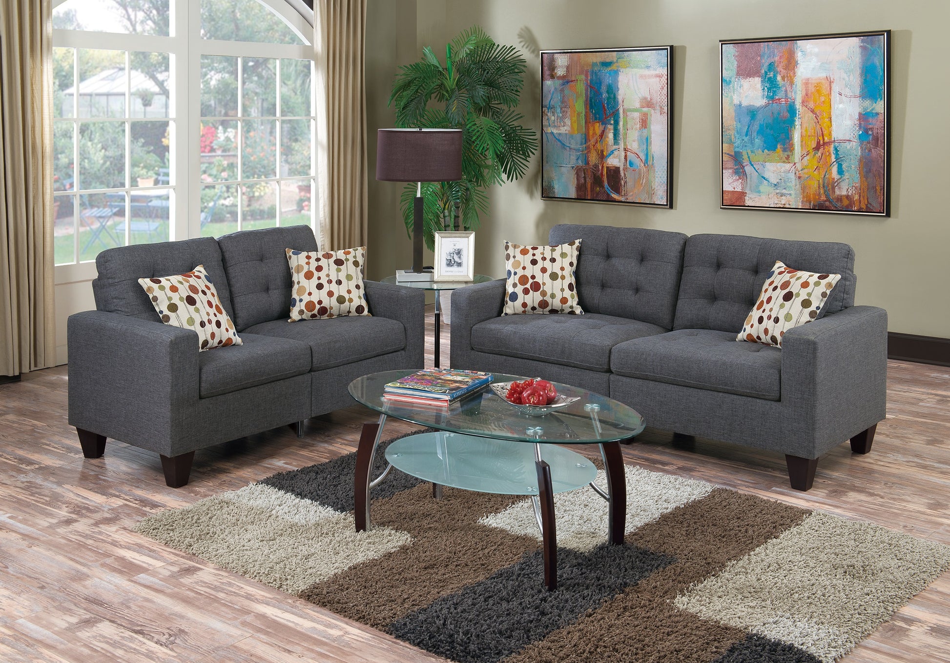 Two dark grey tufted sofas with colorful geometric pillows create a modern living space