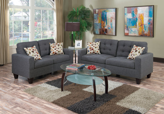 Two dark grey tufted sofas with colorful geometric pillows create a modern living space