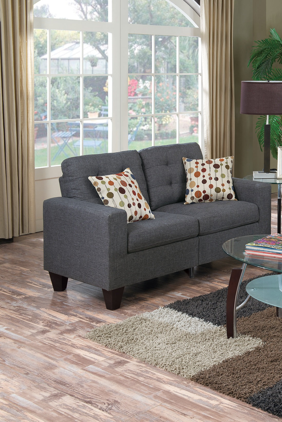 Dark gray tufted loveseat with colorful dot patterned accent pillows a stylish living room sofa