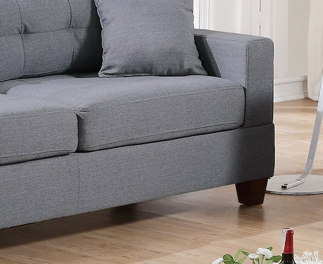 Closeup of a textured gray fabric sofa with button tufting on the back cushion
