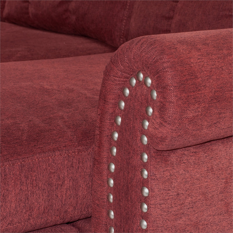 Closeup of a plush burgundy sofa armrest with decorative silver nailhead trim emphasizing texture