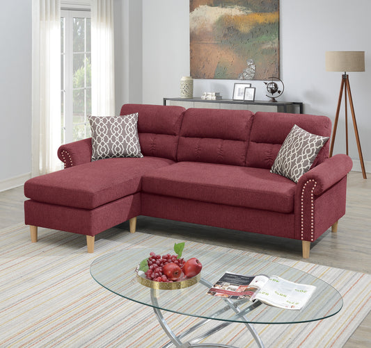 Maroon upholstered sectional sofa with nailhead trim and decorative pillows providing comfortable seating