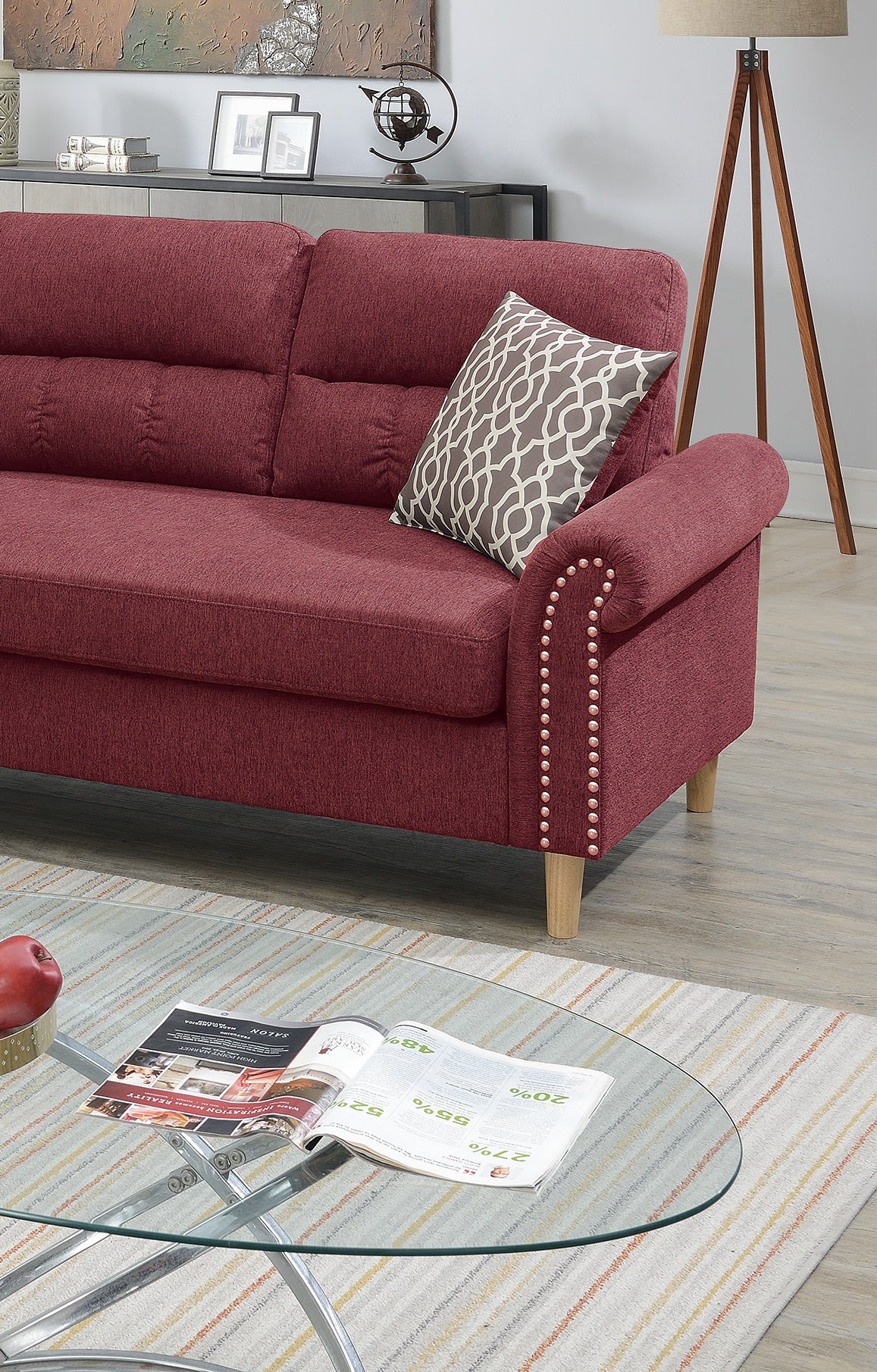 Burgundy fabric sofa with decorative nailhead trim and a geometric accent pillow