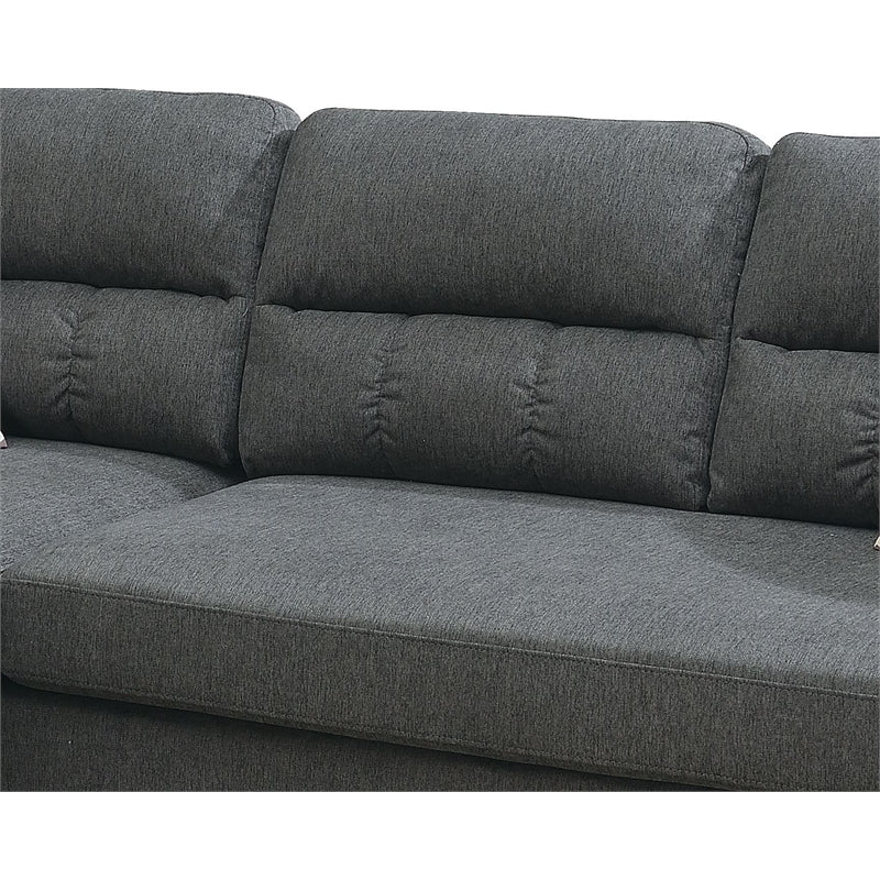 Close up of dark gray fabric sectional sofa with tufted back cushions