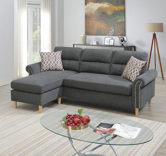 Dark grey fabric sectional sofa with tufted cushions and silver nailhead trim