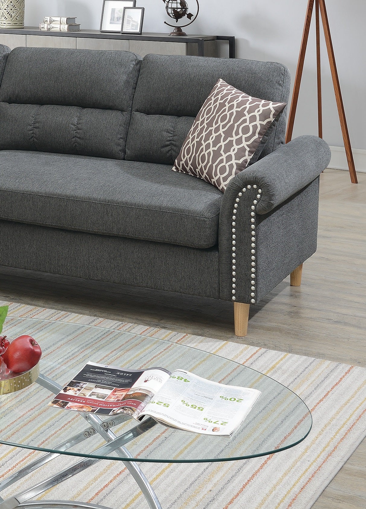 Dark gray upholstered sofa with tufted back cushions and studded armrest for living room