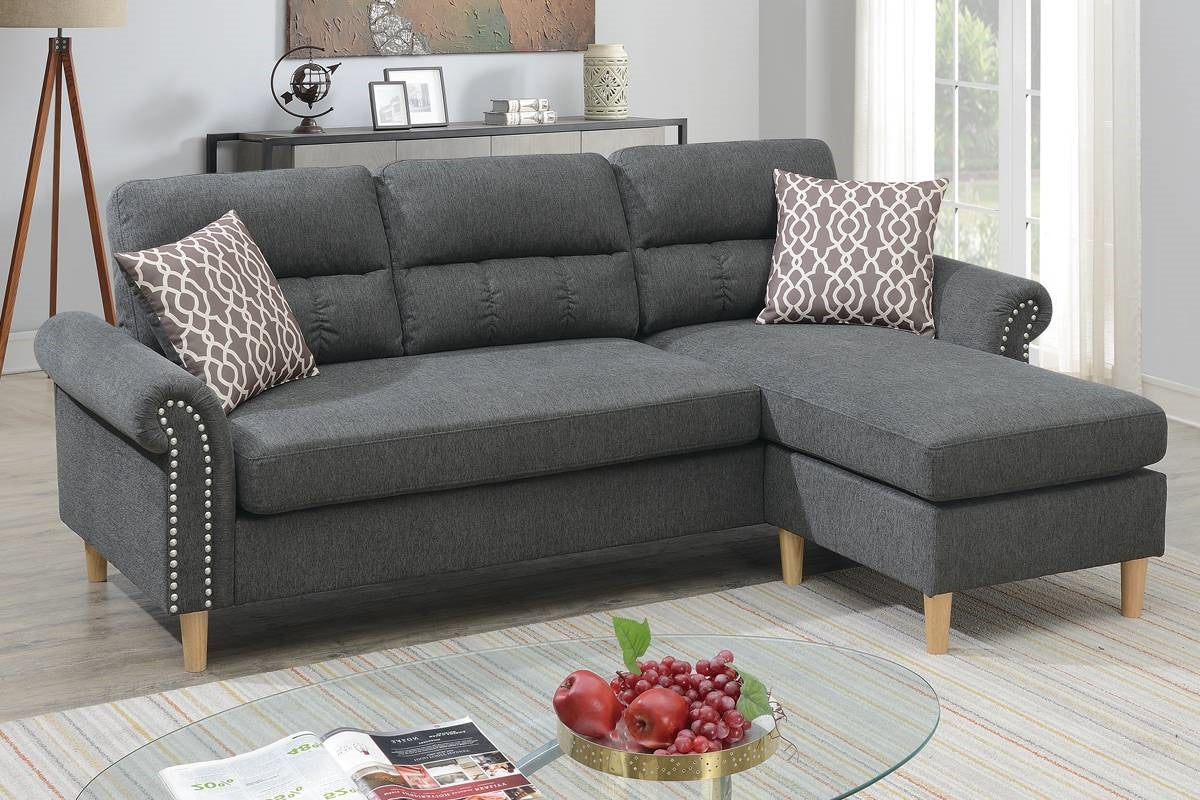 Dark gray fabric sectional sofa with tufted back cushions and silver nailhead trim