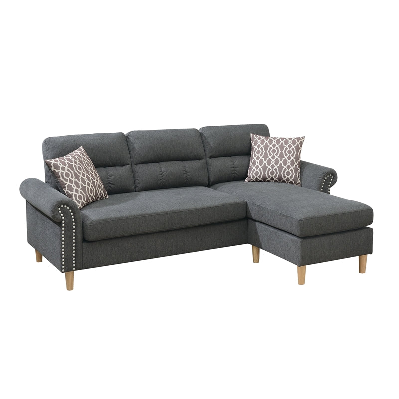 Dark grey fabric sectional sofa with decorative nailhead trim and patterned throw pillows