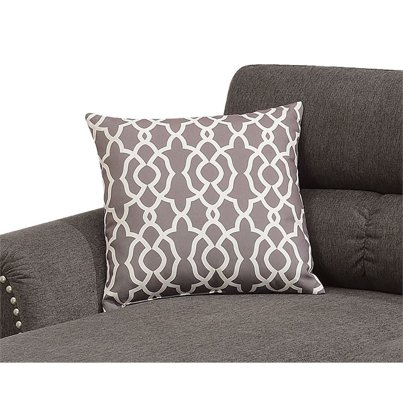 Grey accent pillow with white geometric quatrefoil pattern on a dark grey sofa