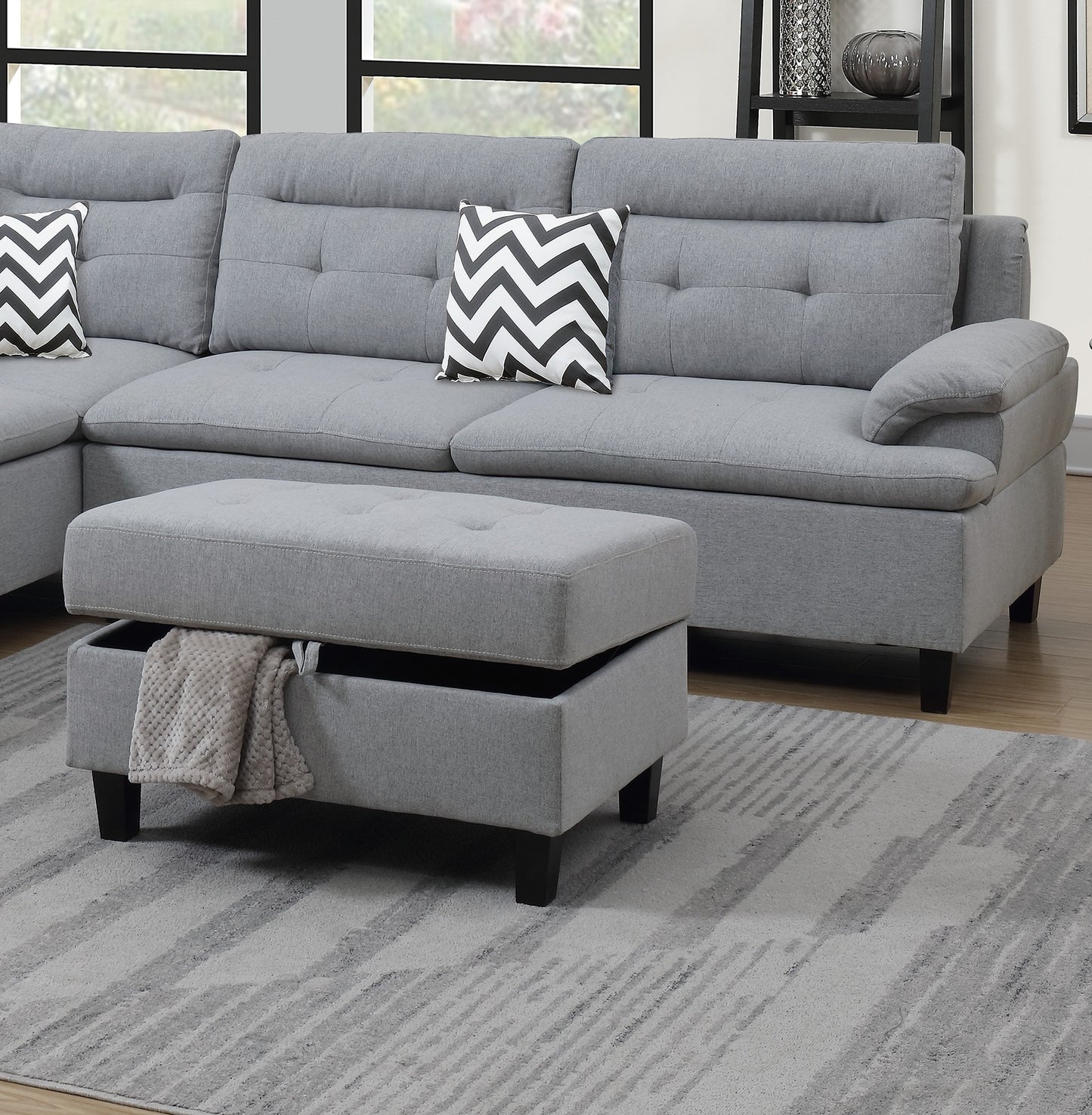 Grey fabric sectional sofa with tufted back cushions and storage ottoman