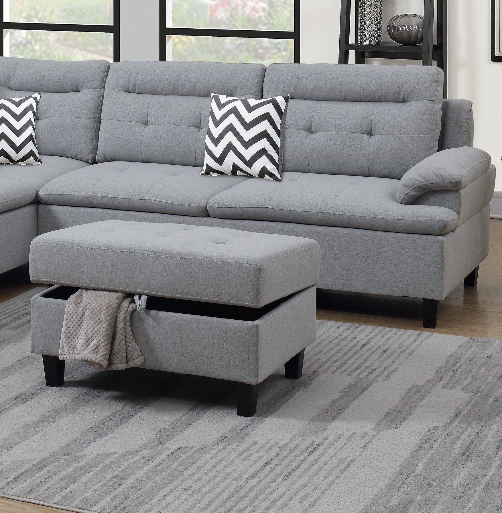 Grey fabric sectional sofa with tufted back cushions and storage ottoman