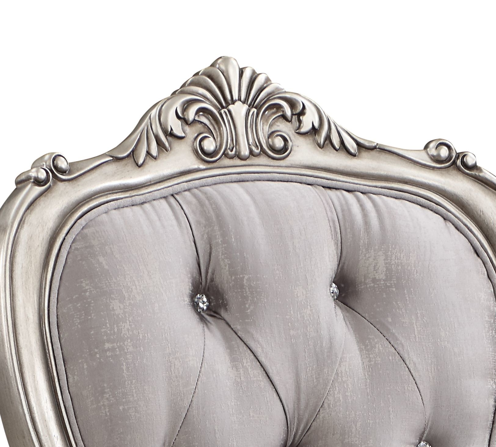 Ornate silver upholstered armchair with diamond tufting and carved wood accents