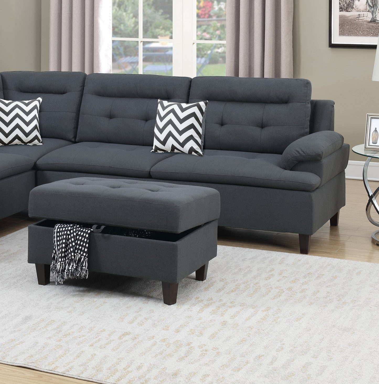 Dark gray tufted sectional sofa with storage ottoman and chevron pillows