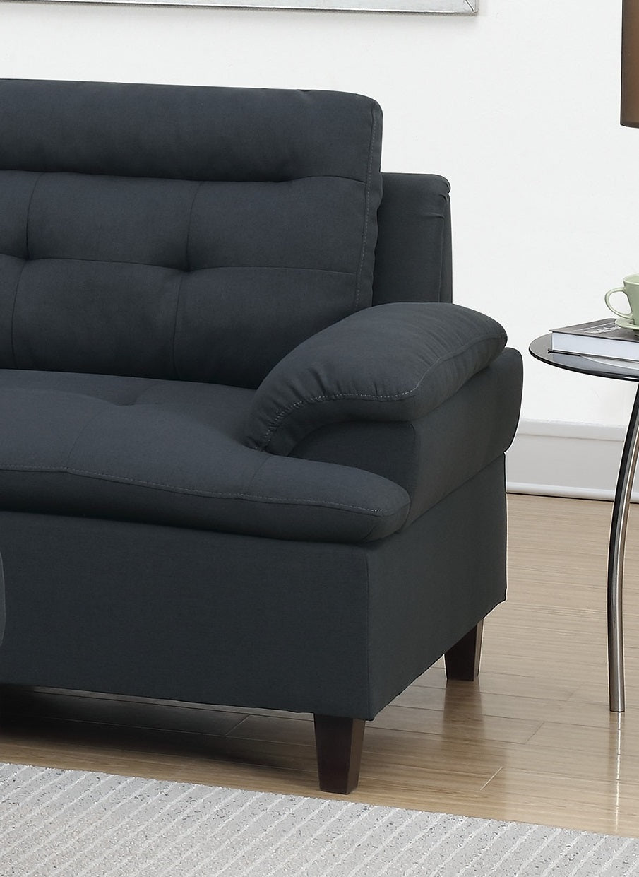 Closeup of a tufted charcoal gray fabric sofa with plush armrest perfect for modern living rooms