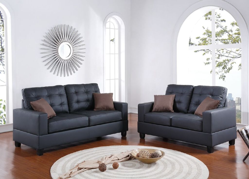 Tufted dark gray faux leather loveseat with brown accent pillows and wooden legs