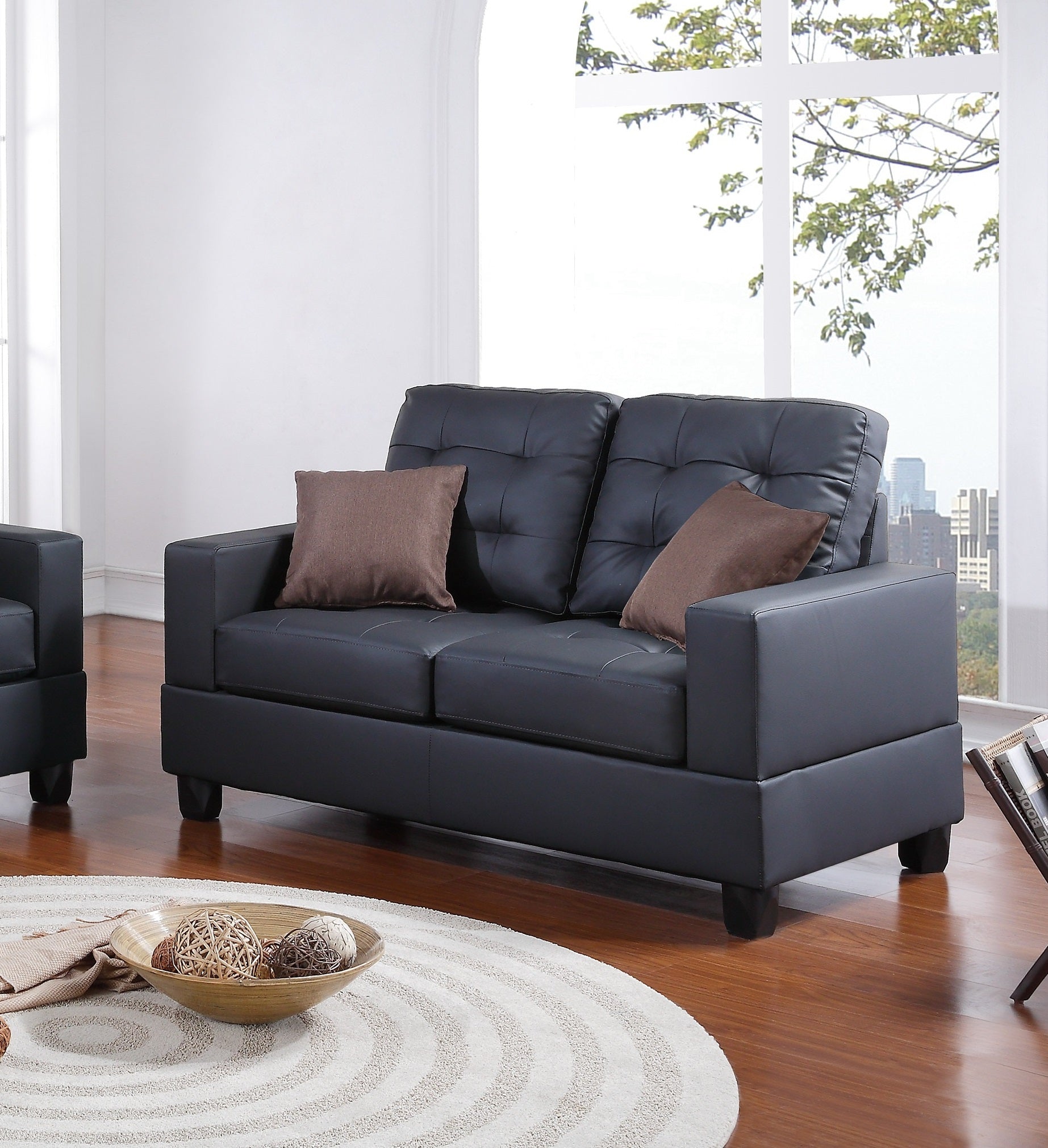 Dark gray faux leather loveseat with tufted back cushions and brown accent pillows