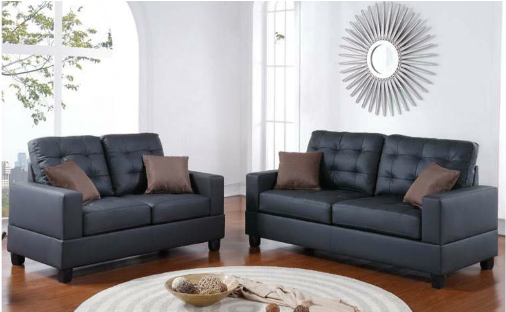 Twoseater black faux leather sofa with tufted cushions and brown accent pillows