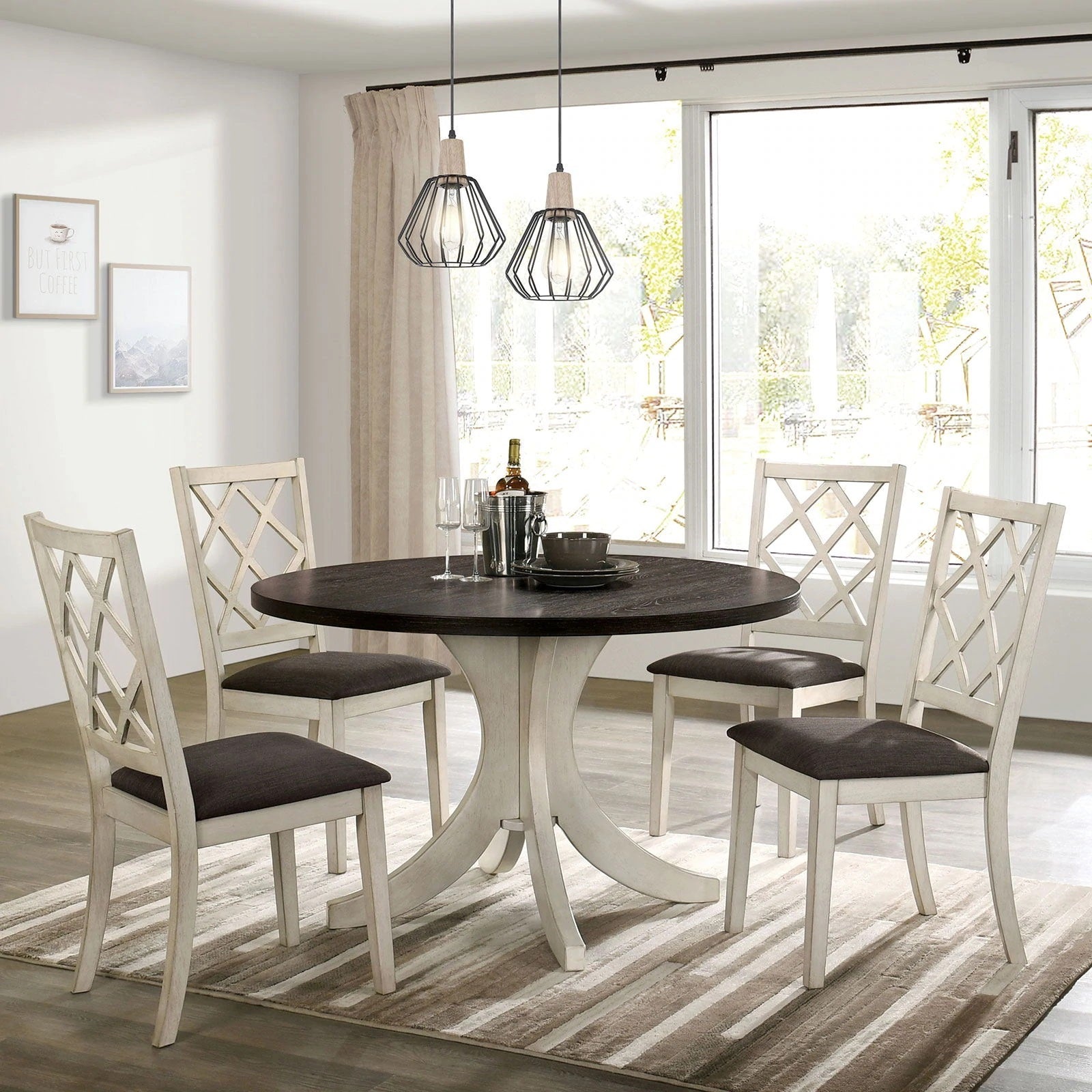 Round dining table with dark wood top and pedestal base seats four in cream chairs