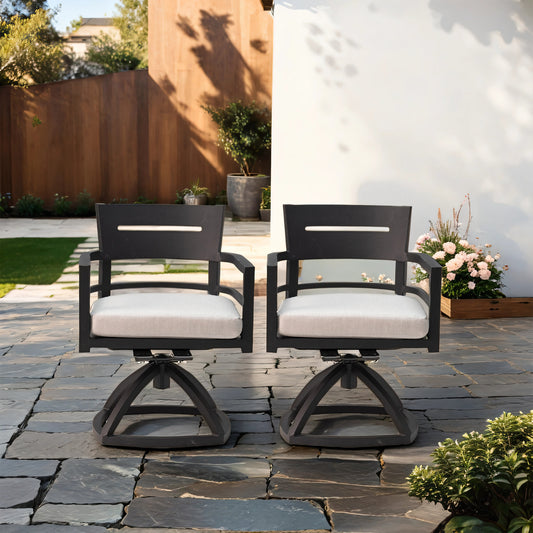 Two black metal patio swivel chairs with light gray cushions on a stone patio