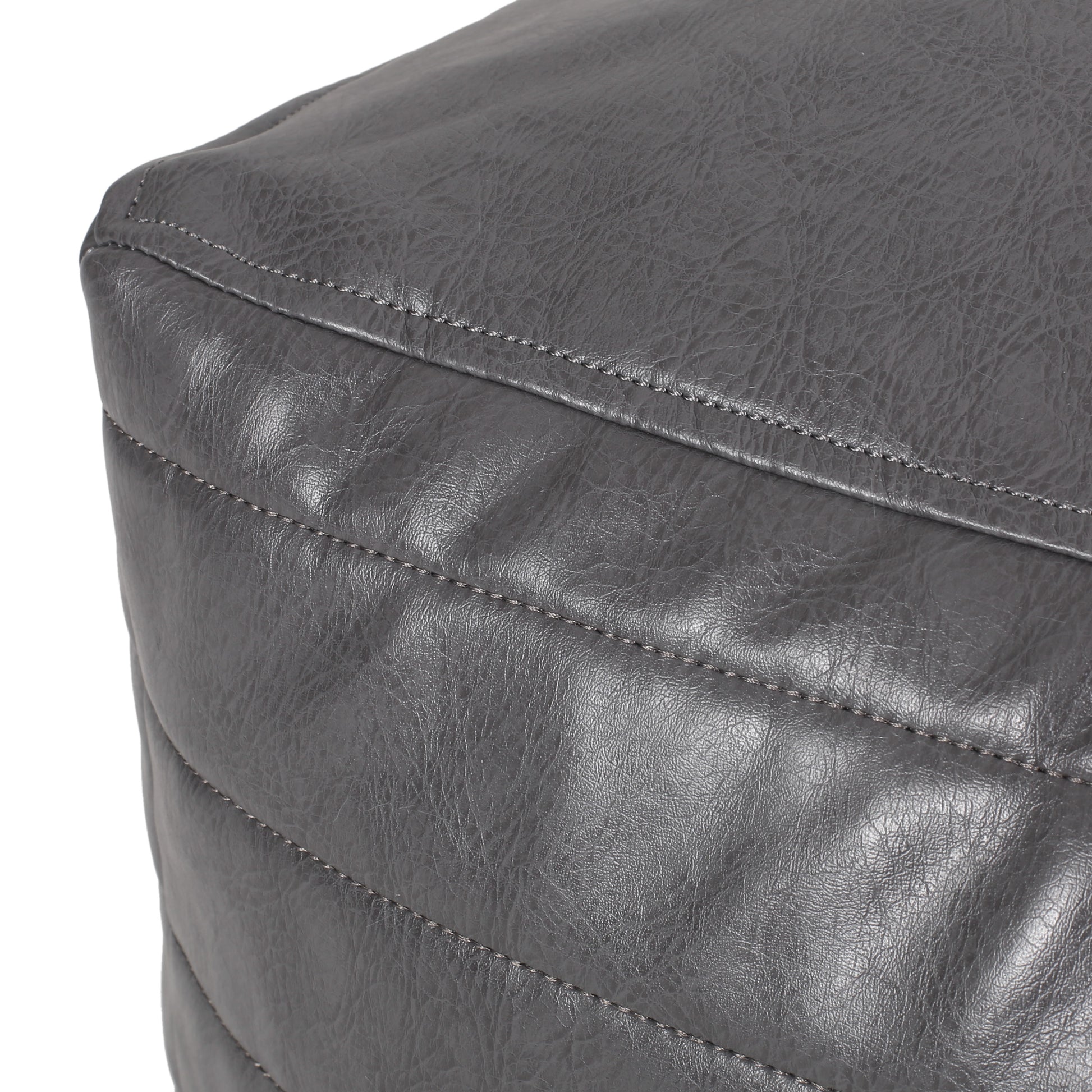 Closeup of grey faux leather ottoman with diamond stitching detail