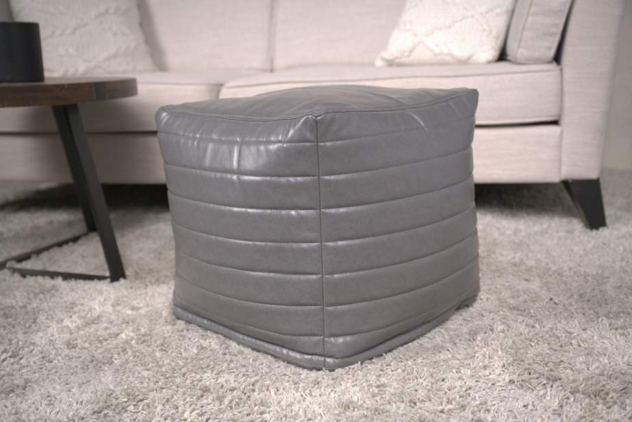 Grey faux leather ottoman with horizontal stitching and cushioned top
