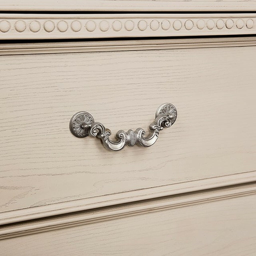 Antique silver drawer pull on a distressed wood dresser in a light cream finish