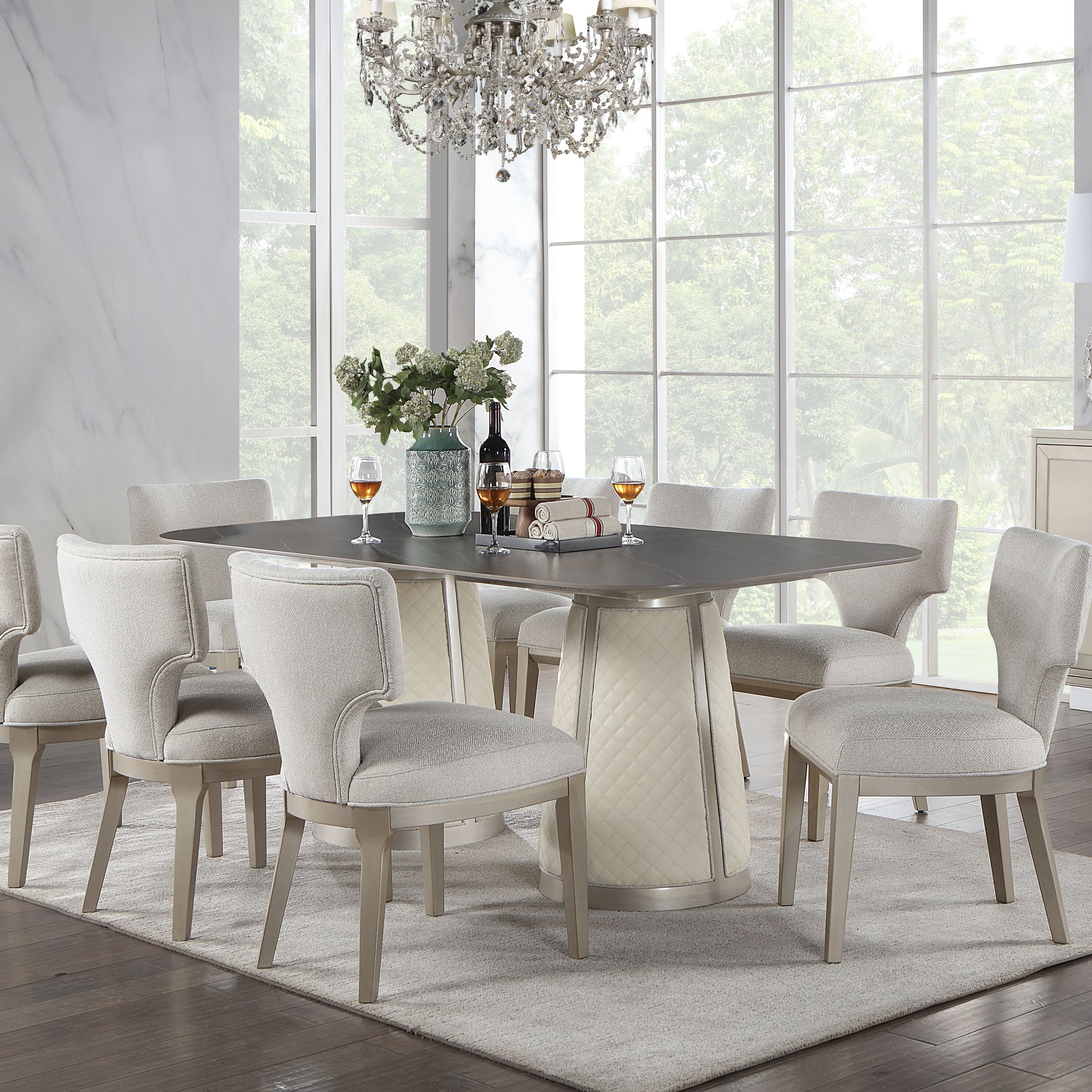 Elegant dining set featuring a dark stone top table with a quilted ivory pedestal base and upholstered light grey chairs
