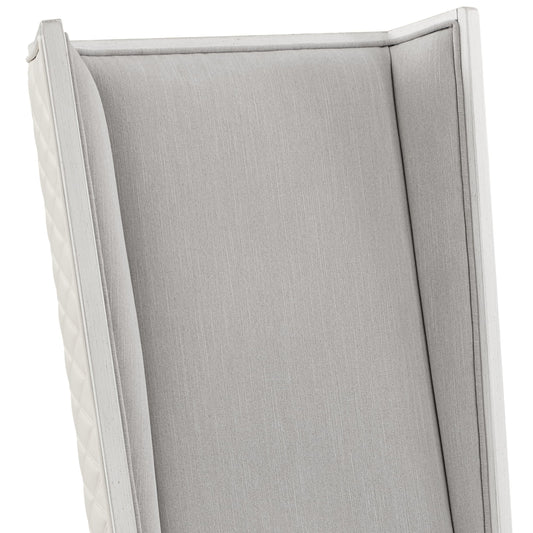 Elegant grey upholstered accent chair with white wooden trim and quilted side panels